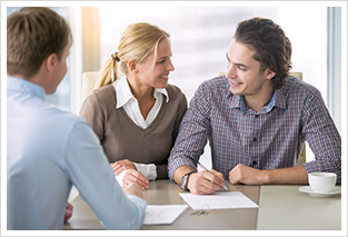 young smiling couple signing with a mortgage broker