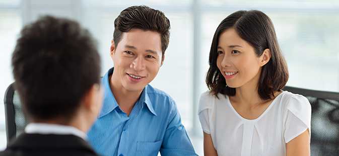 First Time Home Buyer Couple Sitting With Mortgage Agent